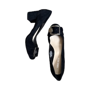 Può includere: Décolleté nere in camoscio con tacco a blocco e chiusura con fibbia. Le scarpe hanno la punta arrotondata e una fibbia color oro. Il marchio "Nine West" è visibile sulla soletta.