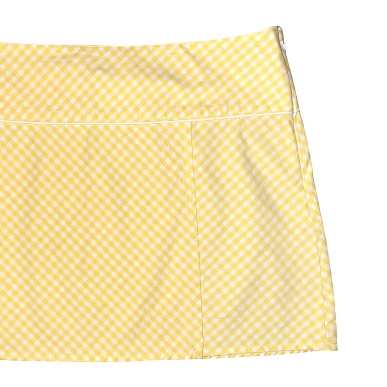 May include: A yellow and white gingham print skirt. The skirt has a straight cut and a white trim along the waistband. The fabric is a lightweight cotton or cotton blend.