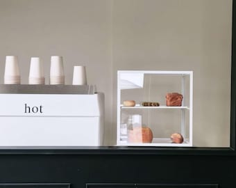 Vitrine de boulangerie moderne en acrylique, avec cadre en métal noir, idéale pour présenter pains et desserts dans les cafés et les boutiques.