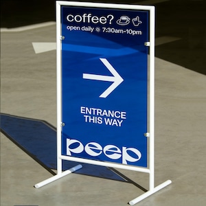 May include: A white metal sign with a blue background. The sign reads "coffee?" with a coffee cup icon, and "open daily 7:30am-10pm." A white arrow points right, with the text "ENTRANCE THIS WAY" below. The word "peep" is at the bottom.