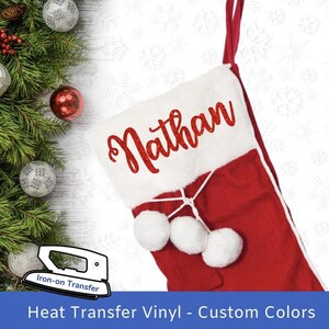 Könnte beinhalten: Roter und weißer Weihnachtssocken mit dem Namen "Nathan" in roten Glitzerbuchstaben auf der weißen Manschette. Der Socken hat weiße Bommeln oben.