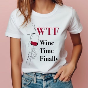 May include: White t-shirt with a black and red graphic design. The graphic features a woman's face with a glass of wine and the text "WTF Wine Time Finally".