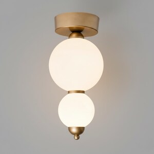 May include: A modern flush mount ceiling light fixture. The fixture features a gold-colored base and accents, with two spherical, frosted glass globes. The light is designed to be mounted directly to the ceiling, providing ambient illumination.