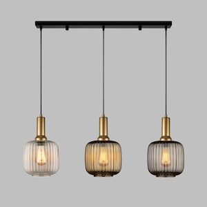 May include: Three black pendant lights with gold accents and ribbed glass shades. The lights are hanging from a black track.