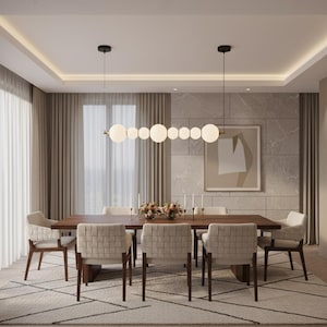 May include: A modern dining room set with a dark wood table, six woven-back chairs, and a patterned rug. A series of spherical lights hangs above the table. The room has neutral tones with beige curtains and a framed abstract artwork.