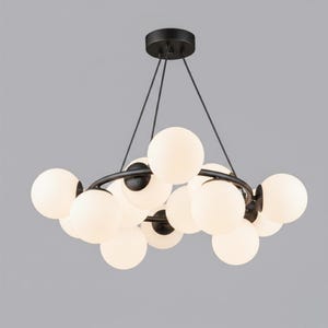 May include: A modern chandelier featuring a black metal frame and multiple spherical, frosted glass light bulbs. The fixture is suspended from the ceiling by thin black wires, creating a contemporary lighting design. The bulbs are evenly spaced around the frame.