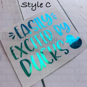 May include: A teal blue vinyl decal with the text "Easily Excited by Ducks" and a small duck illustration. The decal is on a white background.
