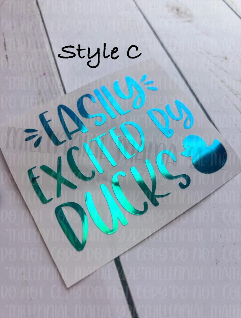May include: A teal blue vinyl decal with the text "Easily Excited by Ducks" and a small duck illustration. The decal is on a white background.