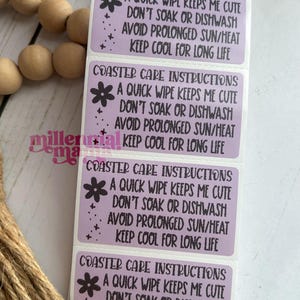 May include: Four rectangular lavender coaster care instruction labels. Each label has the text "COASTER CARE INSTRUCTIONS", a flower graphic, and care instructions: "A QUICK WIPE KEEPS ME CUTE, DON'T SOAK OR DISHWASH, AVOID PROLONGED SUN/HEAT, KEEP COOL FOR LONG LIFE."