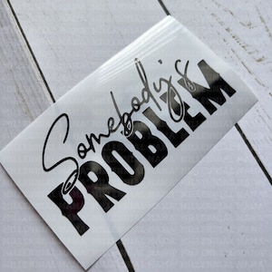 May include: A white sticker with black text that reads "Somebody's Problem". The text is in a bold, cursive font.
