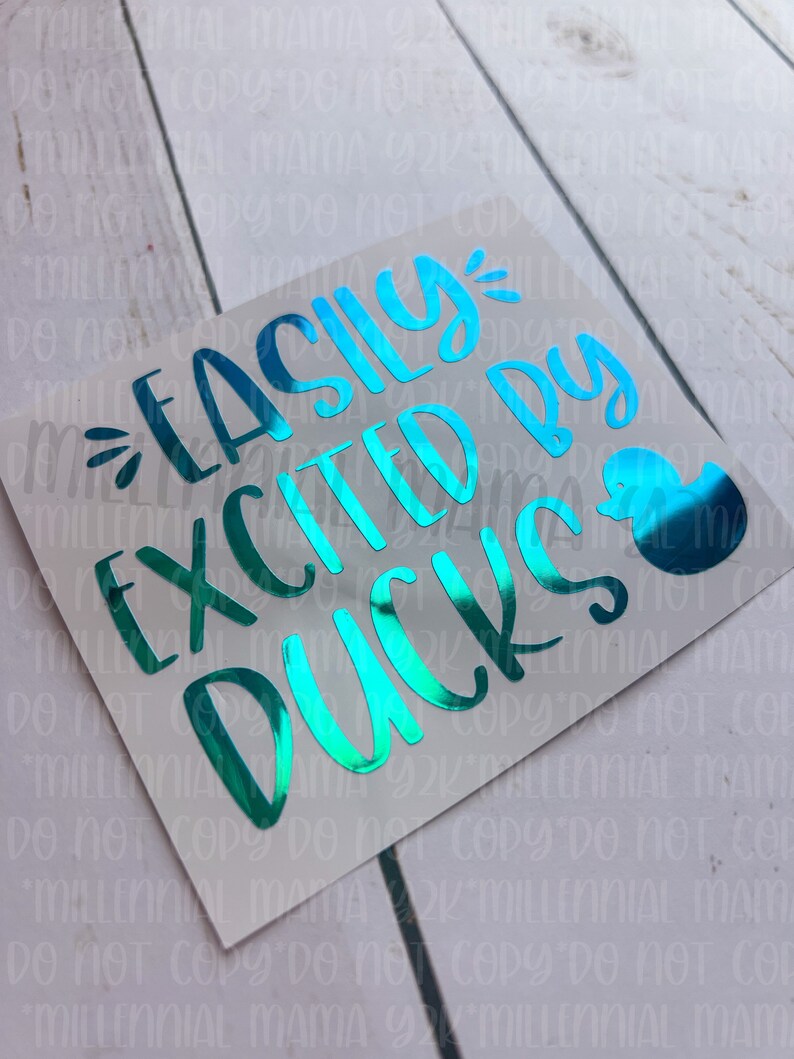 May include: A teal blue vinyl sticker with the text "Easily Excited By Ducks" and a small teal blue duck illustration.