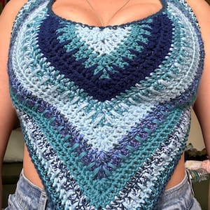 May include: A crocheted halter top in shades of blue, teal, and purple. The top is made with a textured stitch and has a triangular shape.