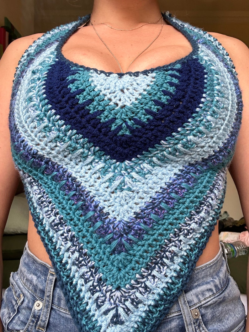 May include: A crocheted halter top in shades of blue, teal, and purple. The top is made with a textured stitch and has a triangular shape.