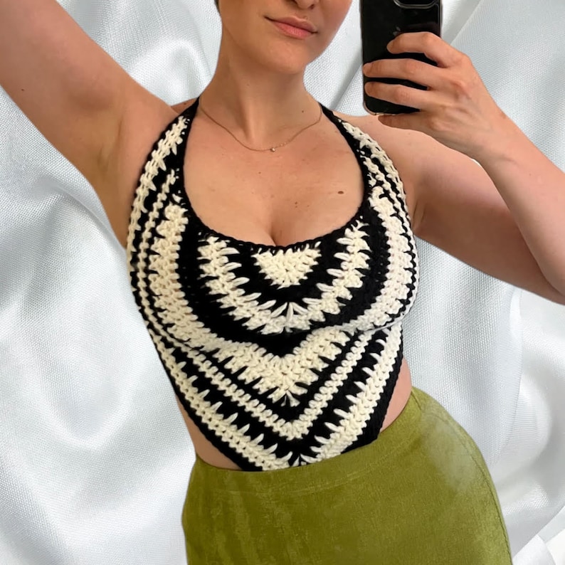May include: A black and white crocheted halter top with a geometric pattern. The top is cropped and has a low neckline.