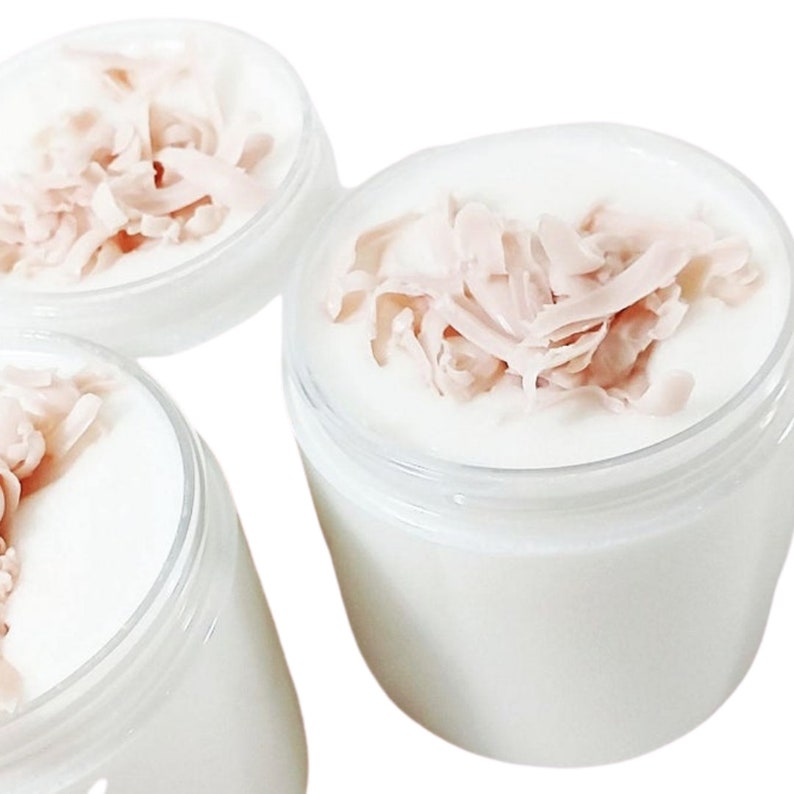 May include: Three clear glass jars with white cream and pink shredded coconut flakes on top.