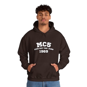 Könnte beinhalten: Ein braunes Kapuzenpullover mit weißem Text, der "MC5 Kick Out The Jams 1969" lautet.