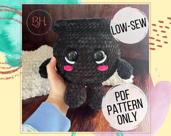 Può includere: Un giocattolo amigurumi in crochet nero con occhi grandi e guance rosa. Il giocattolo ha la forma di un calderone e ha un design a basso cucito. L'immagine include il testo "LOW-SEW" e "PDF PATTERN ONLY".