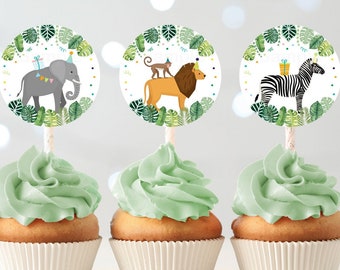 May include: Three green frosted cupcakes with white cupcake liners. Each cupcake has a round, colorful paper topper with a jungle animal wearing a party hat. The toppers feature an elephant, a lion, and a zebra.