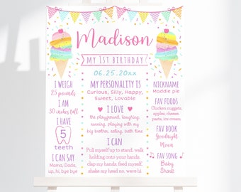 May include: A pink and white printable first birthday sign with a rainbow ice cream cone graphic. The sign includes details about the child, such as their name, weight, height, favorite foods, and favorite book. The text on the sign reads "Madison, My 1st Birthday, 06.25.20xx, I weigh 25 pounds, I am 30 inches tall, I have 5 teeth, I can say Mama, Dada, up, hi, bye bye, My personality is Curious, Silly, Happy, Sweet, Lovable, I love the playground, laughing, running, playing with my big brother, eating, bath time, I can pull myself up to stand, walk holding onto your hands, clap my hands, feed myself, shake my head no, wave hi, Nickname Maddie pie, Fav foods Chicken nuggets, apples, cheese, pasta, ice cream, Fav book Goodnight Moon, Fav song Baby Shark".