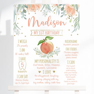 Puede incluir: Un cartel de hitos de primer cumpleaños rosa y dorado con una ilustración de melocotón y detalles florales. El cartel enumera el nombre del niño, Madison, la edad, el peso, la altura, el número de dientes, los alimentos favoritos, los rasgos de personalidad y las cosas que puede hacer.