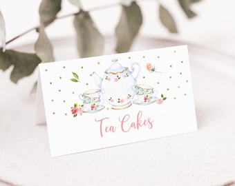 Puede incluir: Tarjeta blanca con fondo de purpurina dorada y una ilustración de acuarela de una tetera y dos tazas de té con flores rosas. El texto "Tea Cakes" está escrito en rosa debajo de la ilustración.