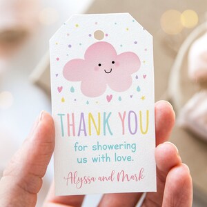 May include: A white thank you tag with a pink cloud with a happy face and raindrops. The text reads "Thank You for showering us with love. Alyssa and Mark".