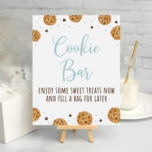 May include: A white sign with blue text that reads "Cookie Bar" and the text "Enjoy some sweet treats now and fill a bag for later". The sign is decorated with brown watercolor cookies and blue and brown chocolate chips.