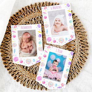Op de afbeelding: Drie witte fotokaarten met kleurrijke snoepranden. Elke kaart heeft een foto van een baby op verschillende leeftijden: pasgeboren, 6 maanden en 1 jaar. De kaarten geven de leeftijd aan.