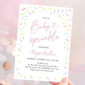 May include: A pink and white baby sprinkle invitation with colorful sprinkles around the border. The text reads "It's a Baby sprinkle honoring Alyssa Miller. Saturday, October 15th, 6:00 PM. The Miller home, 125 West 18th Street, New York, NY 10020. RSVP by October 5th: 917.628.2455 call or text. Registered at Store Names Here."