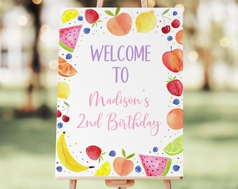 May include: A white welcome sign with a pink and purple border. The sign says "Welcome to Madison's 2nd Birthday". The border is decorated with watercolor illustrations of fruit, including watermelon, bananas, lemons, cherries, strawberries, peaches, and limes.