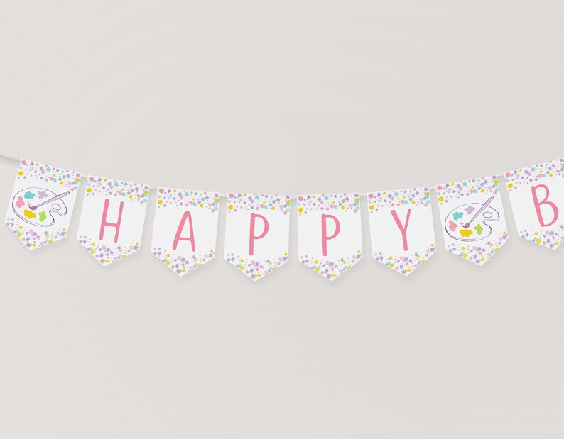 May include: A white banner with pink letters spelling "HAPPY" and a paint palette with a paintbrush on each end. The banner has a white background with a confetti pattern of pink, yellow, and blue dots.