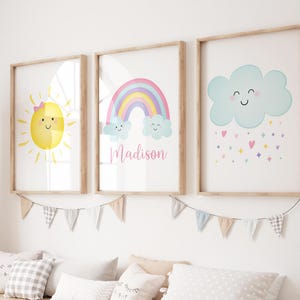 Puede incluir: Tres impresiones enmarcadas con un arco&iacute;ris, un sol y una nube con gotas de lluvia. El arco&iacute;ris es rosa, morado, azul y verde. El sol es amarillo con un lazo rosa. La nube es azul con una cara sonriente. Las impresiones tienen el nombre "Madison" escrito en ellas.