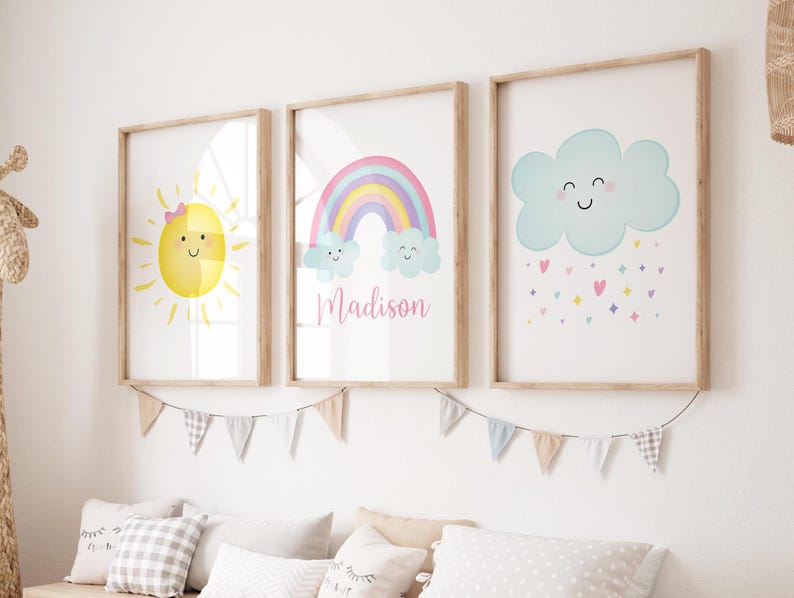Puede incluir: Tres impresiones enmarcadas con un arco&iacute;ris, un sol y una nube con gotas de lluvia. El arco&iacute;ris es rosa, morado, azul y verde. El sol es amarillo con un lazo rosa. La nube es azul con una cara sonriente. Las impresiones tienen el nombre "Madison" escrito en ellas.