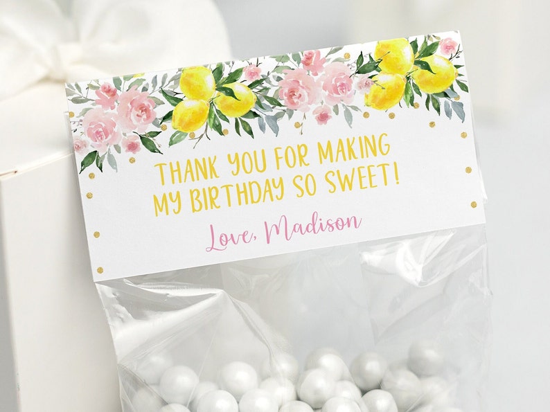 May include: A white favor bag with a pink and yellow lemon themed thank you tag. The tag says "Thank you for making my birthday so sweet! Love, Madison".