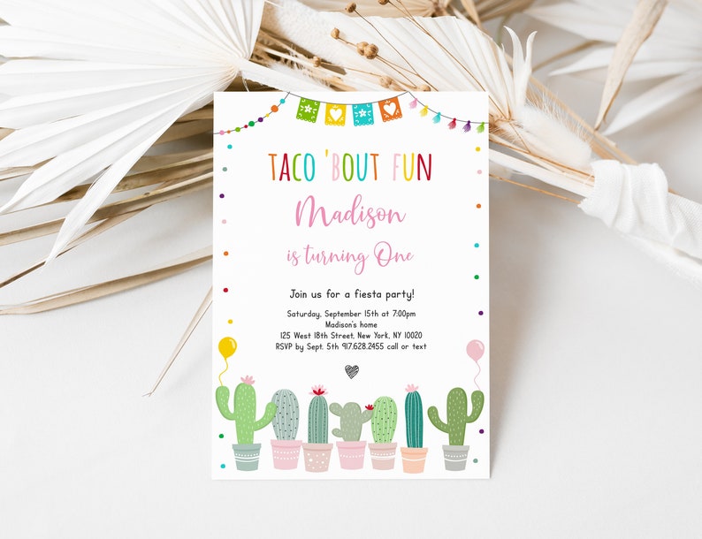 May include: A colorful invitation for a "Taco 'Bout Fun" party celebrating a child turning one year old. The invitation features a cactus theme with a pink banner that says "Taco 'Bout Fun" and "Madison is turning One". The invitation also includes a string of colorful flags and a cactus illustration.