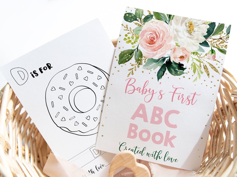 May include: A pink and white floral design with gold glitter accents on a white card. The card says "Baby's First ABC Book Created with Love".