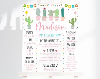 May include: A pink and green cactus-themed first birthday milestone poster with the name Madison. The poster lists the child's weight, height, number of teeth, favourite foods, books, songs, and things they can do.