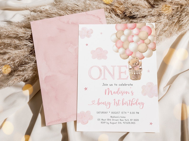 May include: Pink and white first birthday invitation with a teddy bear in a hot air balloon. The invitation says "Join us to celebrate Madison's beary 1st birthday" and includes the date, time, and location of the party.