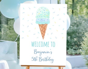 May include: A white sign on a wooden easel with an ice cream cone illustration and the text "WELCOME TO Benjamin's 5th Birthday" in blue. The ice cream cone is light blue and green with sprinkles. Balloons are in the background.