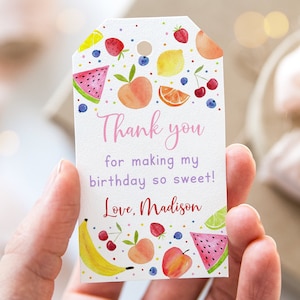 May include: A white thank you tag with a colourful fruit design. The tag says "Thank you for making my birthday so sweet! Love, Madison".