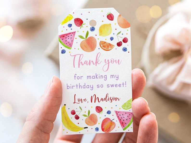 May include: A white thank you tag with a colourful fruit design. The tag says "Thank you for making my birthday so sweet! Love, Madison".