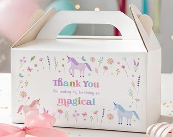 以下が含まれることがあります： ユニコーン、花、蝶で飾られた、ハンドル付きの白いパーティーギフトボックス。ボックスには、カラフルな文字で「Thank You for making my birthday so magical」と書かれています。ピンクのリボンと紙吹雪が前景にあります。