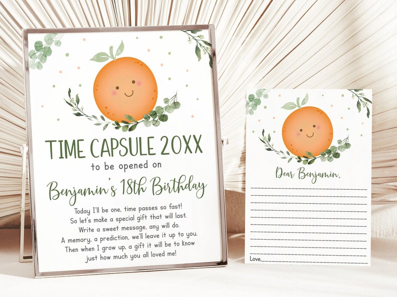Puede incluir: Un letrero de c&aacute;psula del tiempo enmarcado y una tarjeta a juego. El letrero dice "TIME CAPSULE 20XX para abrir en el 18 cumplea&ntilde;os de Benjamin" con una ilustraci&oacute;n de naranja sonriente y vegetaci&oacute;n. La tarjeta dice "Querido Benjamin" con l&iacute;neas para escribir.