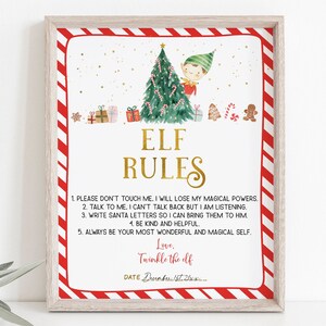 May include: A framed print with a festive design. The print features the text "ELF RULES" in gold lettering, along with a watercolor illustration of an elf, a Christmas tree, and gifts. The border is red and white striped.
