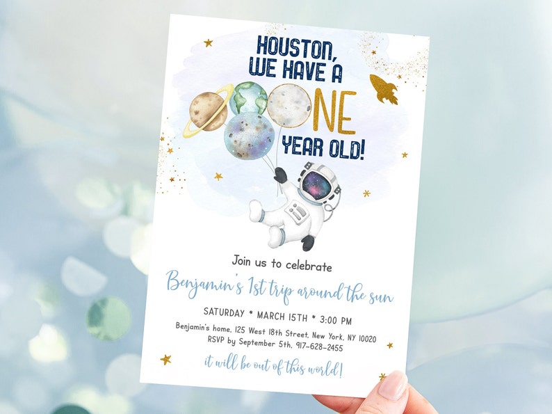May include: A blue and gold astronaut-themed first birthday party invitation with a cartoon astronaut holding balloons shaped like planets. The text reads "Houston, we have a one year old!" and "Join us to celebrate Benjamin's 1st trip around the sun".