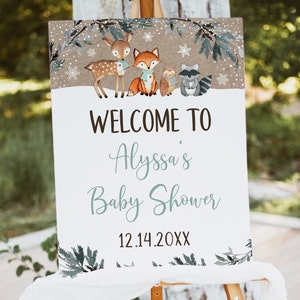 May include: Welcome to Alyssa's Baby Shower sign with a winter woodland theme. The sign features a deer, fox, owl, and raccoon in a snowy forest setting. The date 12.14.20XX is printed at the bottom.