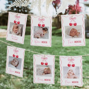 Puede incluir: Un conjunto de seis tarjetas de fotos rosas y blancas con ilustraciones de cerezas y texto que dice "Recién nacido", "Un mes", "Dos meses", "Tres meses", "Cuatro meses" y "Cinco meses".