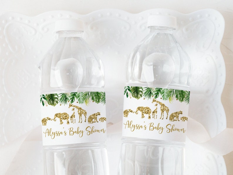 May include: Two clear plastic water bottles with white labels. The labels have a green tropical leaf design with gold glitter animal silhouettes. The text on the labels reads "Alyssa's Baby Shower".