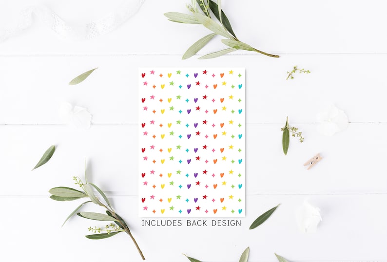 Peut inclure: Une carte blanche avec un motif color&eacute; de c&oelig;urs et d'&eacute;toiles. Le texte "INCLUDES BACK DESIGN" est imprim&eacute; en bas de la carte.