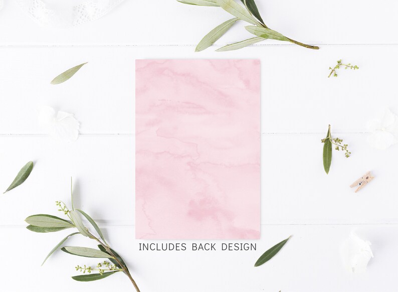 Puede incluir: Una tarjeta rosa en blanco con textura de m&aacute;rmol. La tarjeta est&aacute; sobre una superficie de madera blanca con ramitas verdes y flores blancas.
